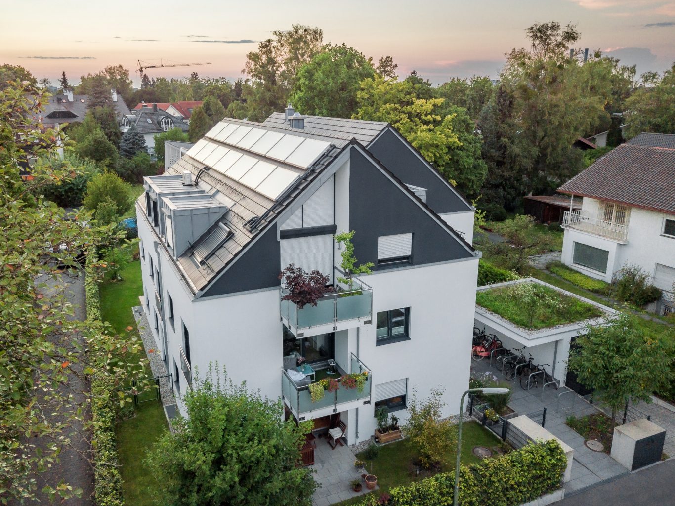 München - Solln Moderne Wohnanlage mit Solarpanelen und begrünten Balkonen, umgeben von Bäumen.