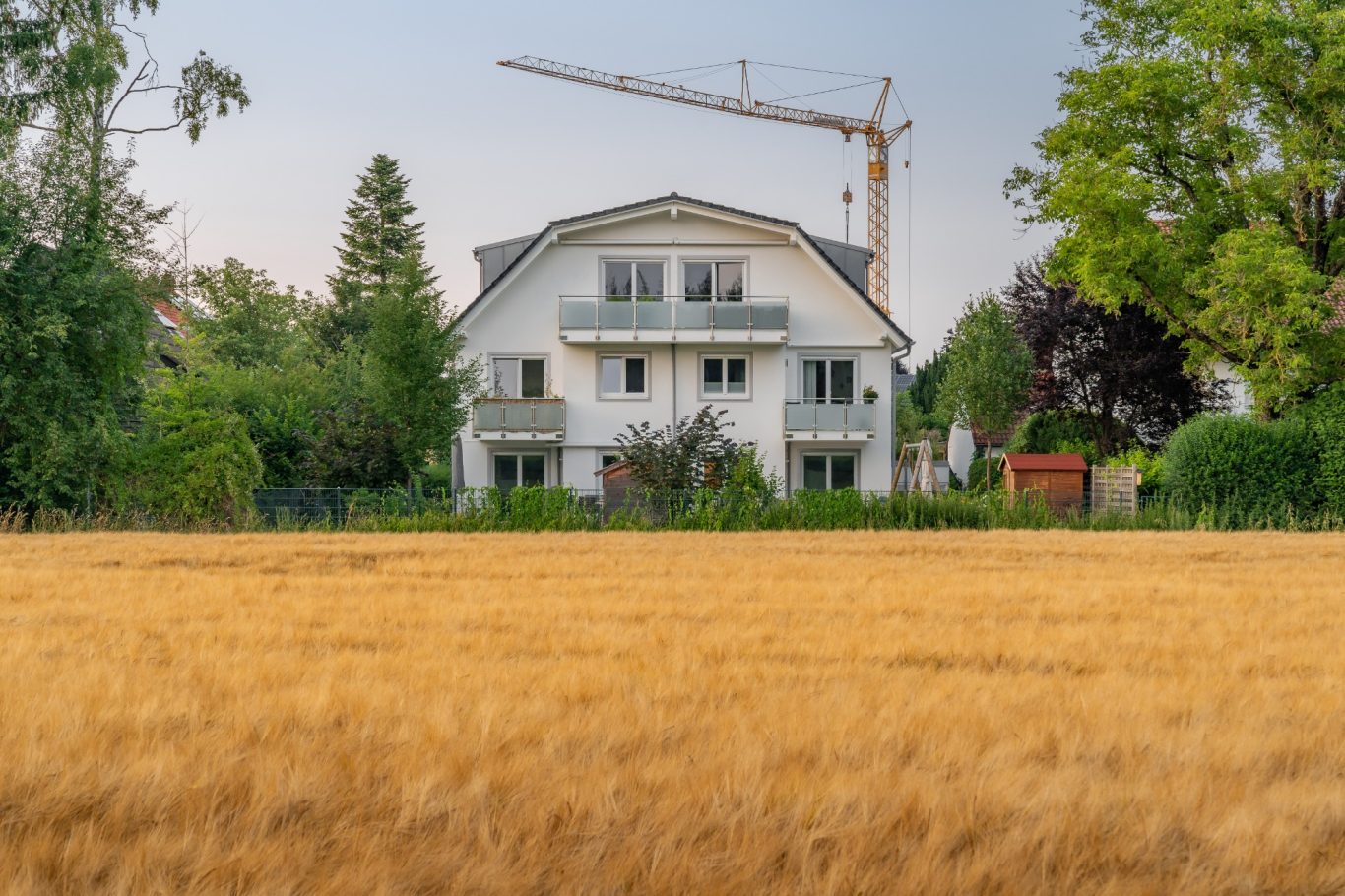 München - Trudering Helles Wohnhaus mit grüner Umgebung und einem Kran im Hintergrund.