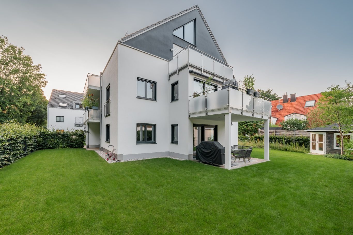 München - Solln Moderner, zweigeschossiger Wohnhausbau mit Balkon und grünem Garten.
