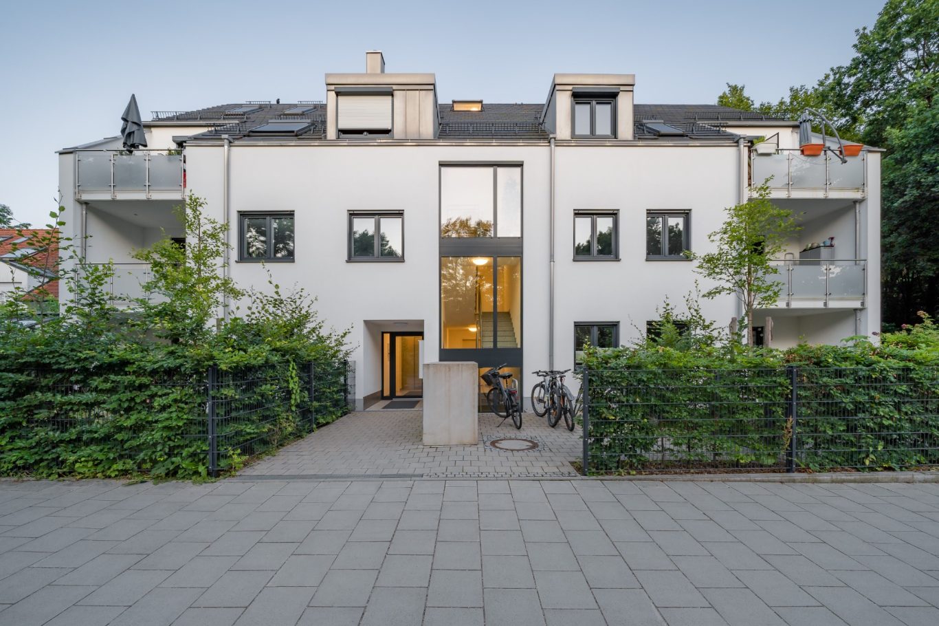München - Berg am Laim Modernes, dreistöckiges Wohngebäude mit Balkonen und umgebender Begrünung.