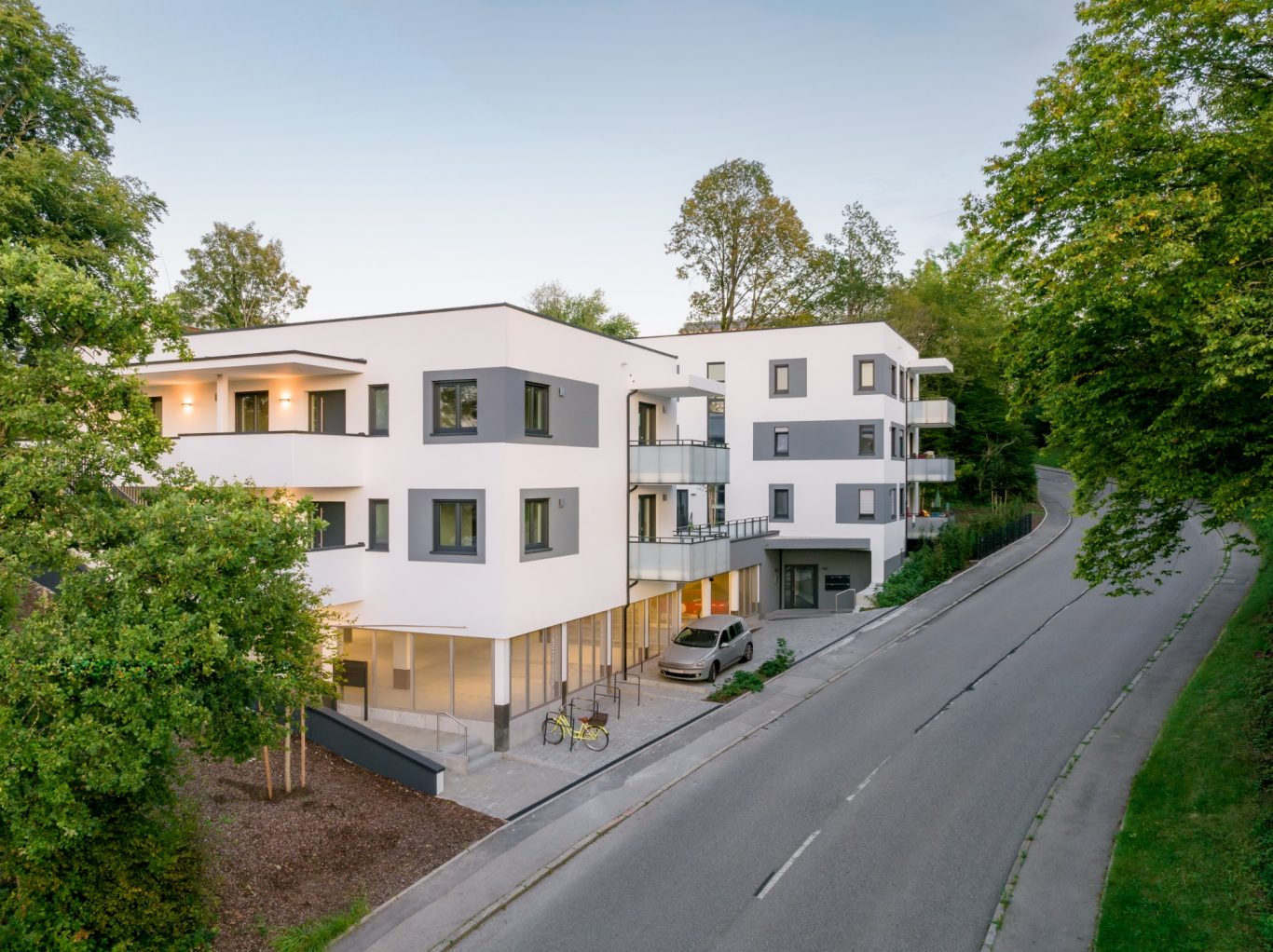 Gauting Moderne Wohngebäude mit Balkonen, umgeben von Bäumen an einer ruhigen Straße.