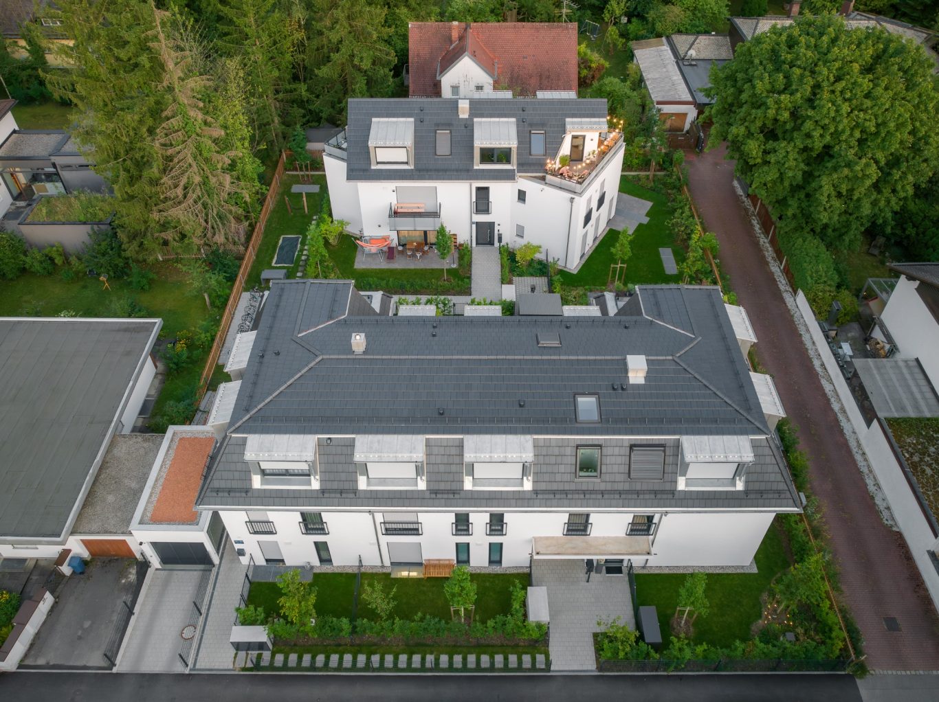 München - Trudering Moderne Wohngebäude mit grünem Innenhof und umgebenden Bäumen.